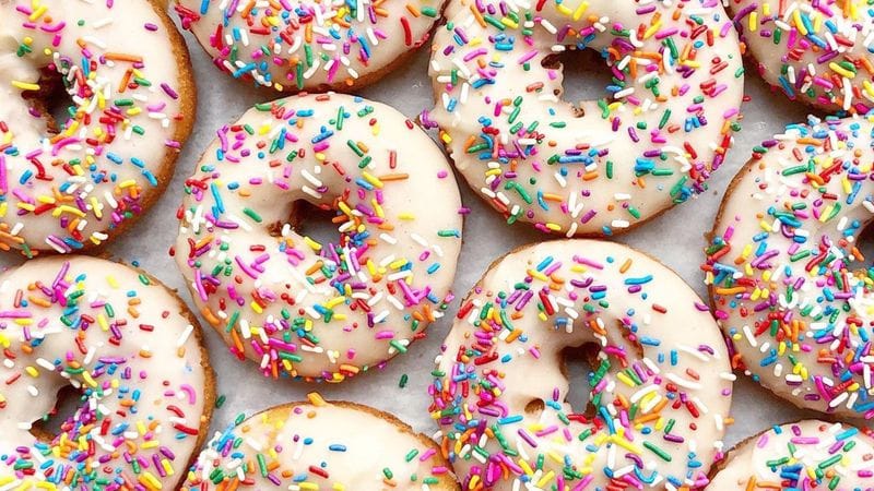 Colorful glazed donuts with rainbow sprinkles, overhead view of multiple pastries