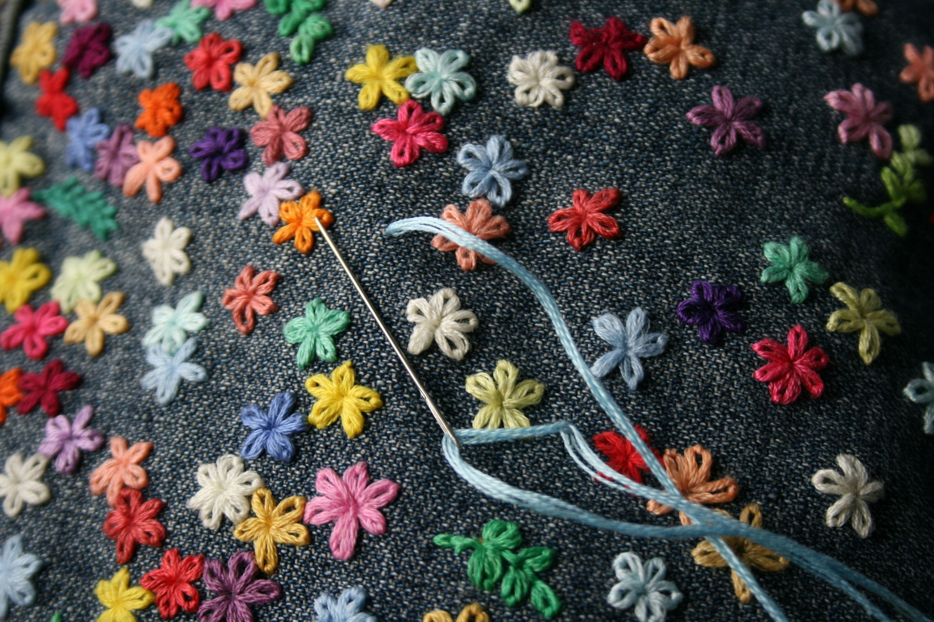 Embroidered colorful floral pattern with small flowers on dark fabric
