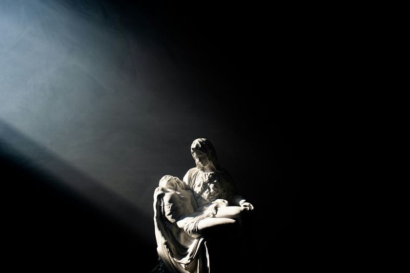 Musician singing into microphone on dark stage with dramatic spotlight
