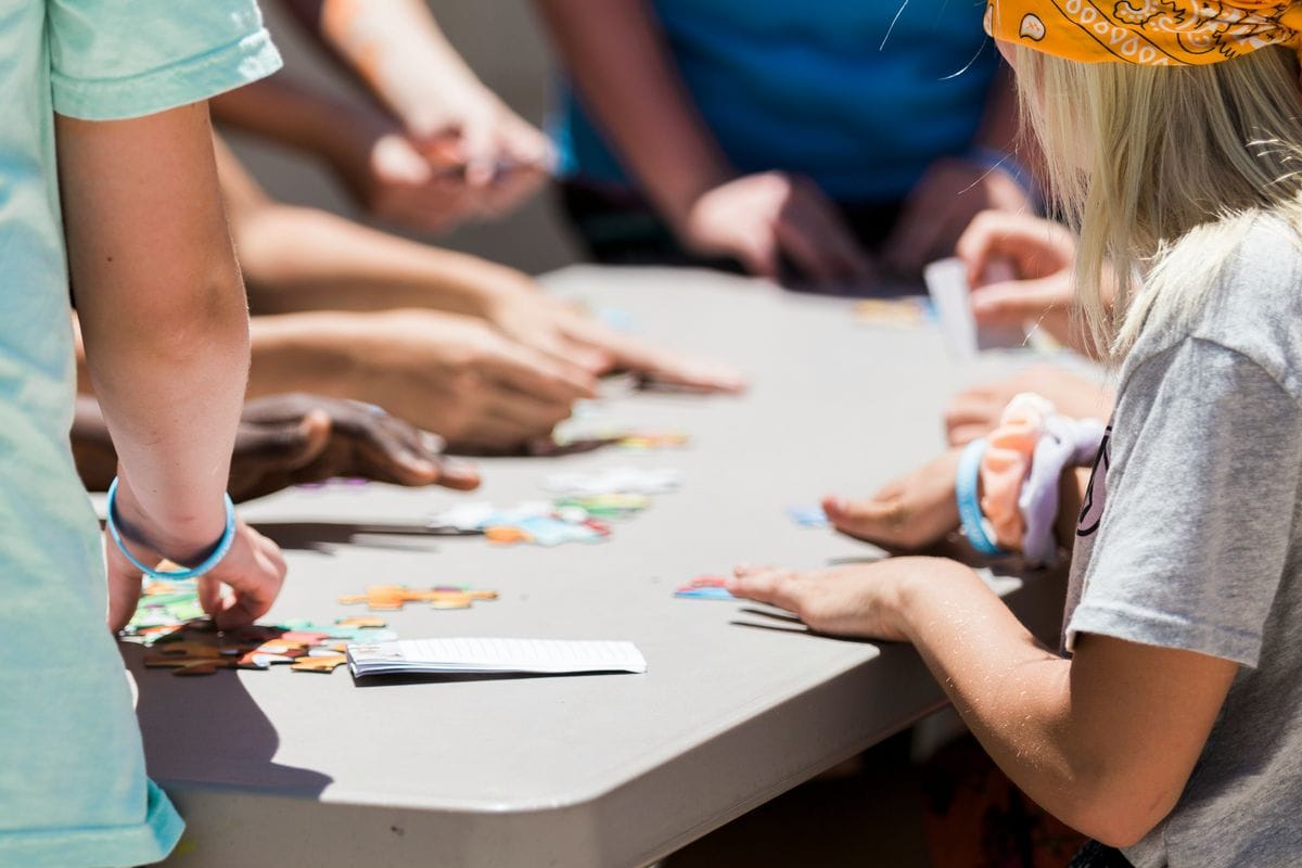 Children's hands playing board game at table, pieces and game board visible